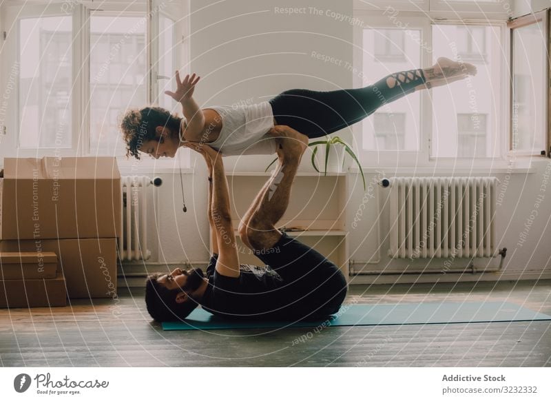 Hipster couple practicing yoga together at home acroyoga balance athletic exercise floor modern apartment trust sport position hipster wellness young adult