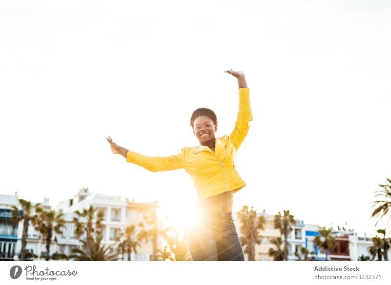 Joyful female smiling and jumping woman happy bounce hands up stylish joyful african american smile jacket bright cute attractive positive healthy charming fit