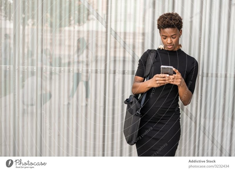 Concentrated female using mobile near urban building woman smartphone message street african american focused concentrated stylish dress black social media