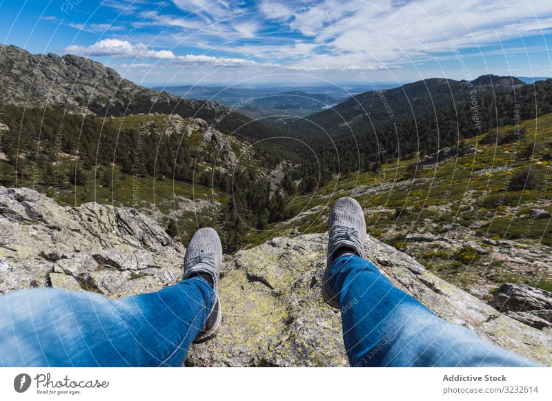 Person sitting dangling legs on stone above mountain valley cloud sky nature travel park forest landscape scenic hill rocky rural green scenery blue beautiful