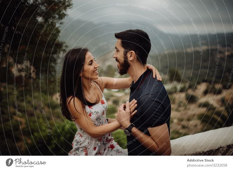 Loving couple embracing while standing against rural valley embrace love happy smile hugging countryside summer green foggy hill casual young adult nature