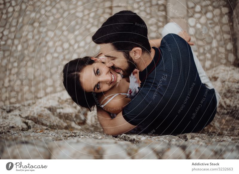 Happy couple kissing while sitting on stone street town love happy romantic affection playful casual embrace cuddle cobbled summer rural young adult city