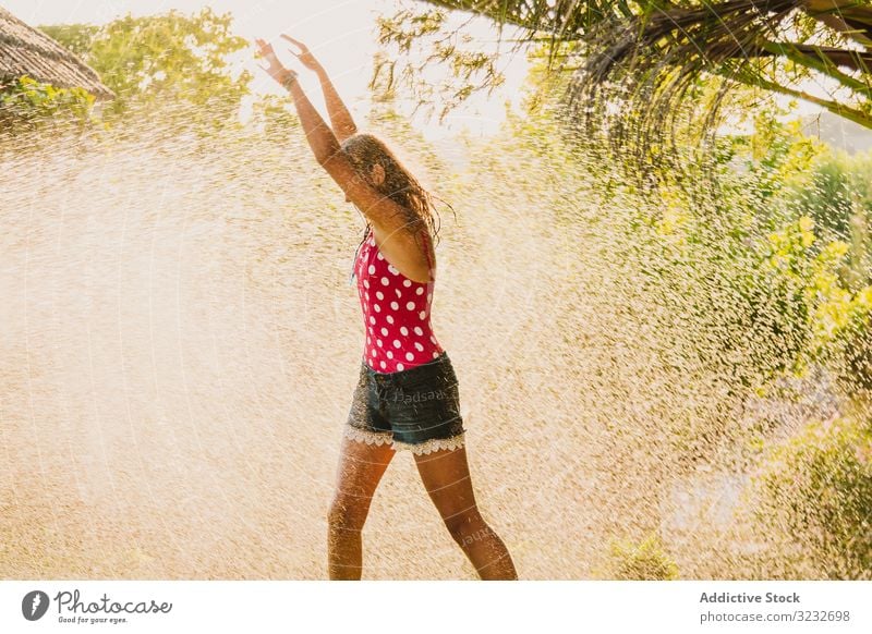 Cheerful teenager having fun with jet of water garden laugh summer weekend girl excited lifestyle rest relax stream clean clear joy delighted optimistic glad