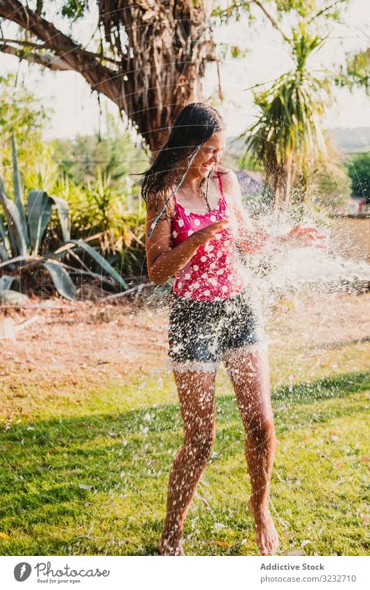 Cheerful teenager having fun with jet of water garden laugh summer weekend girl excited lifestyle rest relax stream clean clear joy delighted optimistic glad