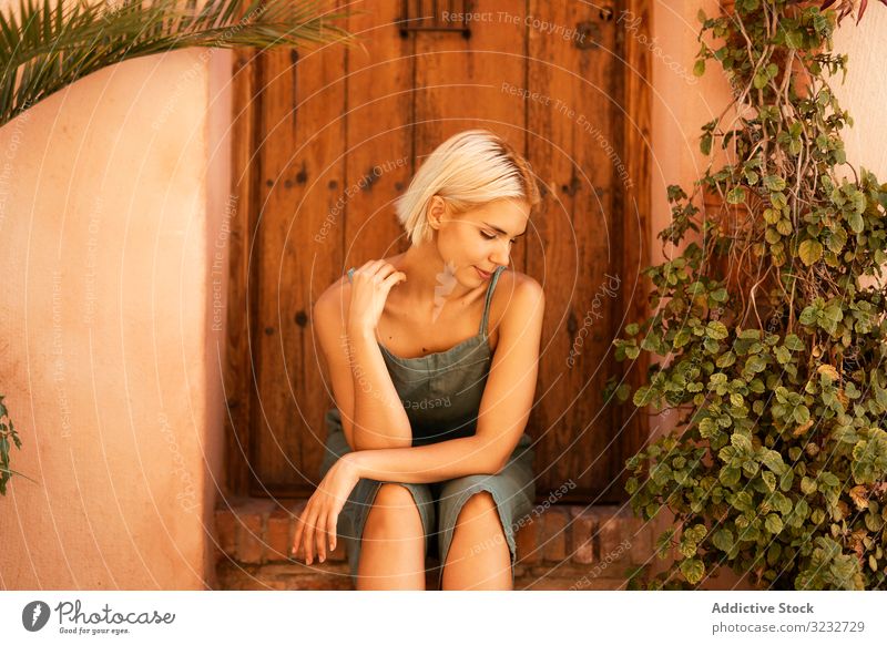 Young female sitting on doorstep woman plant yard garden suburb flora growth vegetation young horticulture estate home cozy blond harmony idyllic dreamy lady