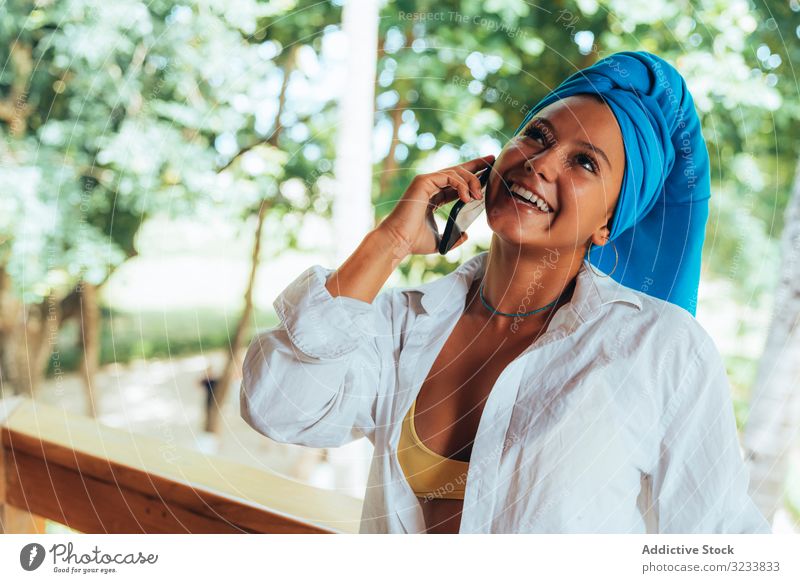 Woman with turban speaking on mobile phone woman positive smile smartphone using head wrap tanned attractive colorful greenery young happy fun photo costa rica