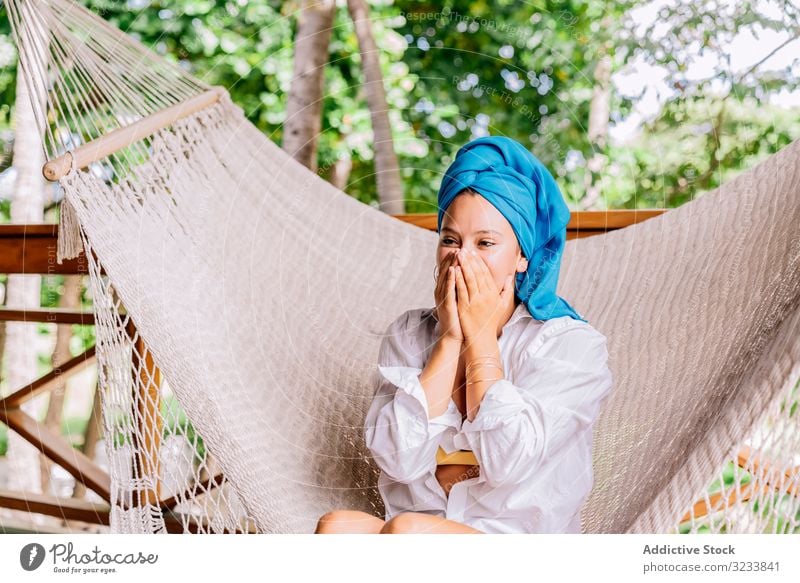 Woman in turban resting in hammock woman happy smile touching face sit terrace tree greenery shirt peaceful costa rica young relax summer comfortable lifestyle