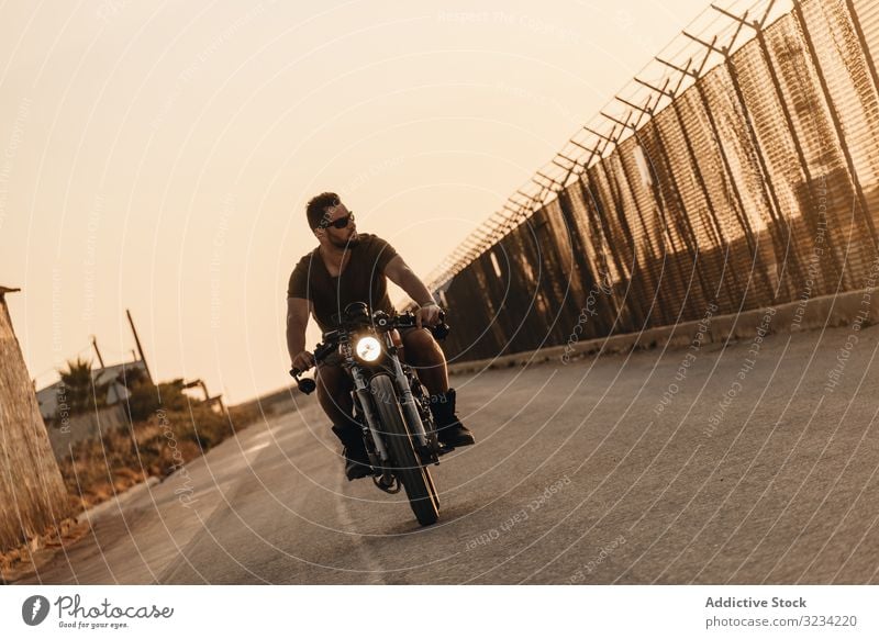 Strong man driving motorcycle drive road sunglasses serious strong male beard ride deserted transport bike biker freedom travel engine power transportation