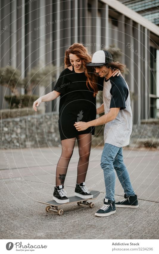 Teenage boy helping girlfriend to skate on road teenage skateboard learn couple together fun practice happy support cheerful urban cool modern generation ride