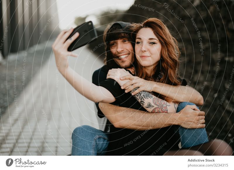 Skaters sitting on road and taking selfie on smartphone couple cool teen skateboard modern urban love together style hipster skater tattoo social media embrace