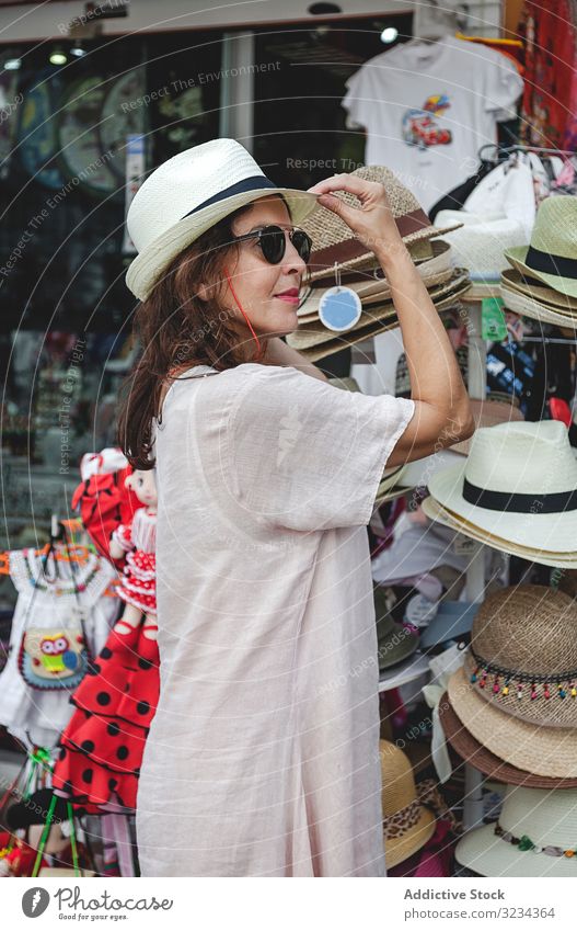 Woman choosing summer hat on street market woman straw hat choose shopping try fitting accessory serious focused confident decision clothing apparel size sale