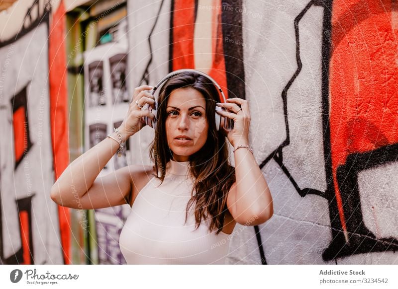 Woman listening to music and using smartphone woman headphones summer graffiti concrete street urban street style grunge social media smile happy gadget