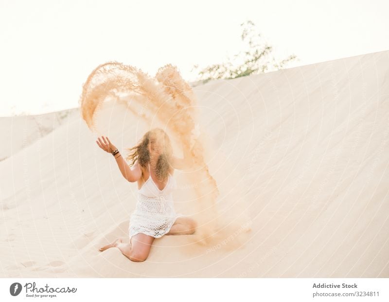 Woman having fun throwing sand in desert woman dune summer tropical vacation adult beautiful relax travel holiday playful recreation activity freedom active