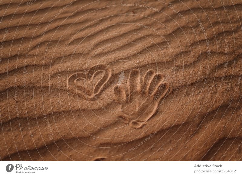 Heart drawn in sand and trace of palm on beach heart seaside hand print shape romantic symbol summer tropical vacation adult woman relax travel activity freedom