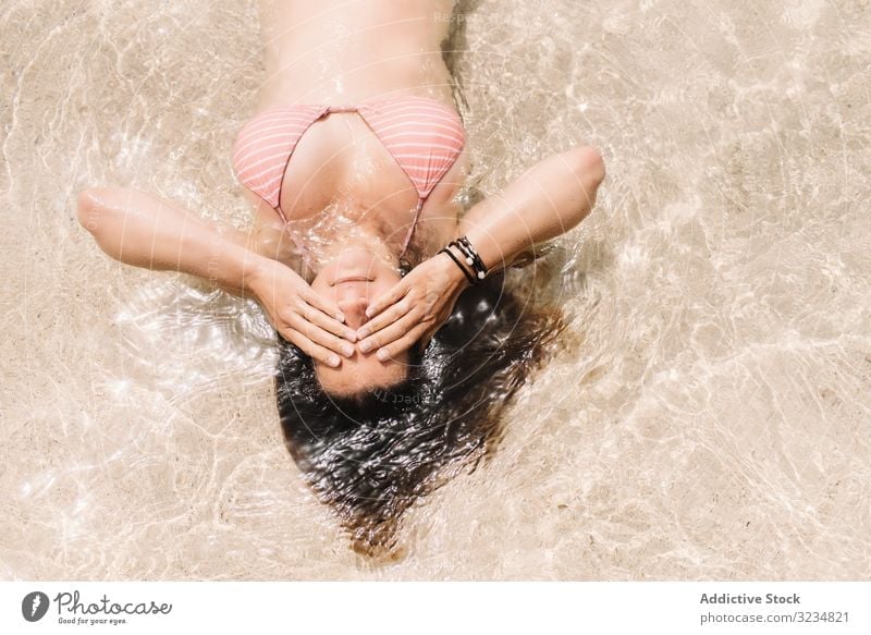 Woman in swimsuit lying in water on seashore woman seaside swimming summer beach leisure beautiful vacation swimwear coast floating cheerful holiday relaxation