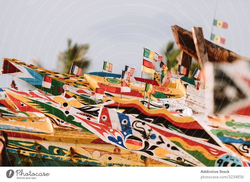 Boats with colorful fronts in harbor boat port town ornament flag shabby old cloudless sky gambia aged weathered grungy wooden lumber timber nobody clear blue