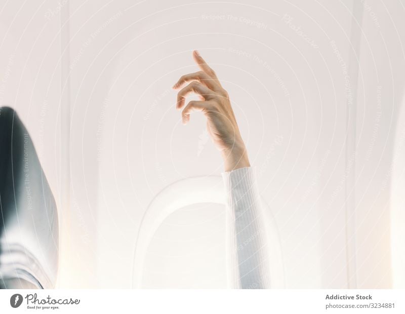 Person in white sweater raising hand up in plane light salon fly attention aircraft expression travel adult concept calm relaxed sitting question communication