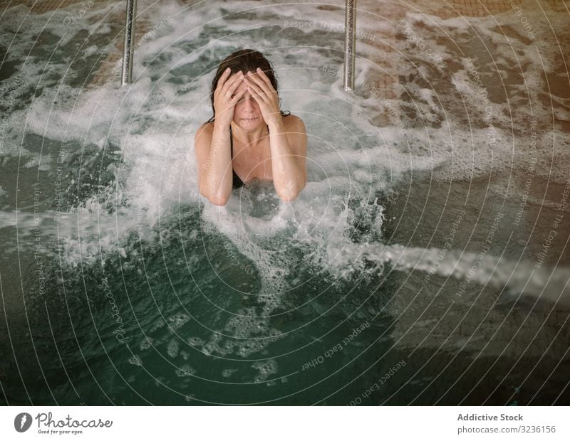 Woman relaxing in bath with hydro massage woman pool spa wave aqua procedure covering face water foam wellness sanitary leisure health female resort swim lady