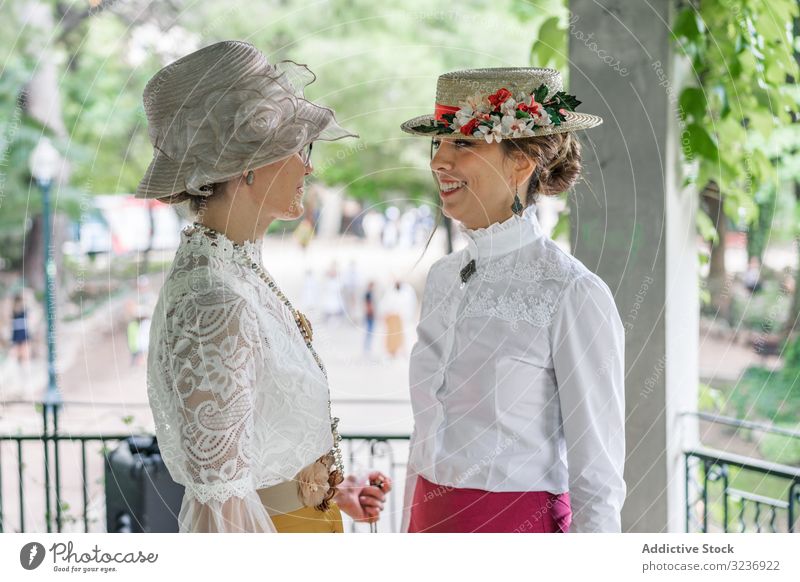 Vintage female friends speaking in garden women smile vintage park blouse hat costume elegant summer old fashioned classic accessory retro outfit lady