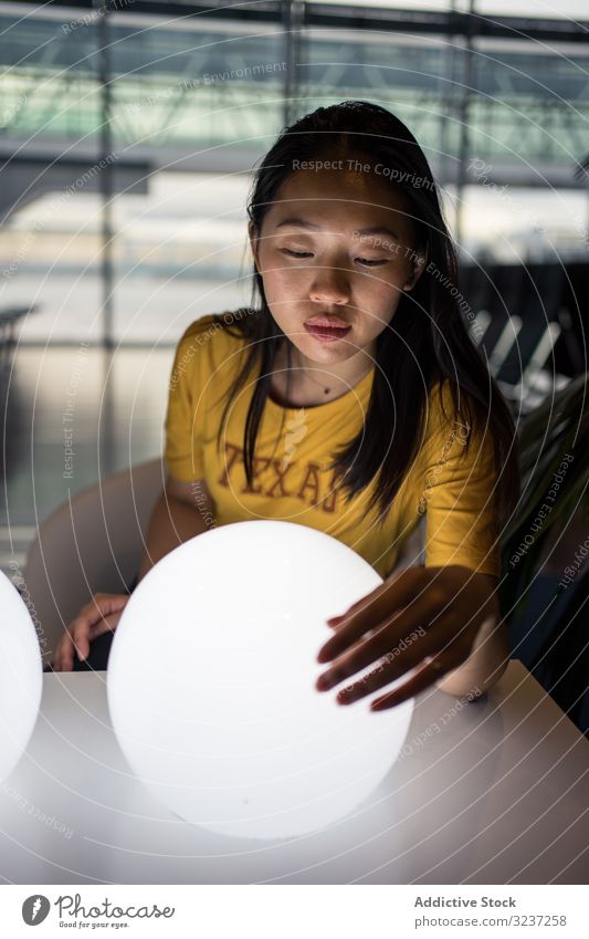 Asian woman examining round lamps on table light creative excitement hall illuminated female interior asian art design electrical power light bulb