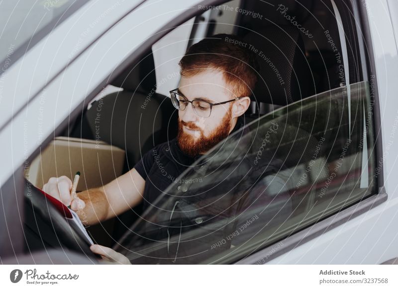 Courier filling papers while preparing for delivery of order to client in car courier attentive man write thoughtful check analysis report service account work