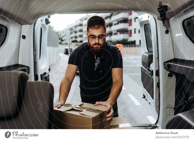 Courier taking out cartons of car for delivery completion man courier box shipment upload thoughtful careful street order service attentive distribution package