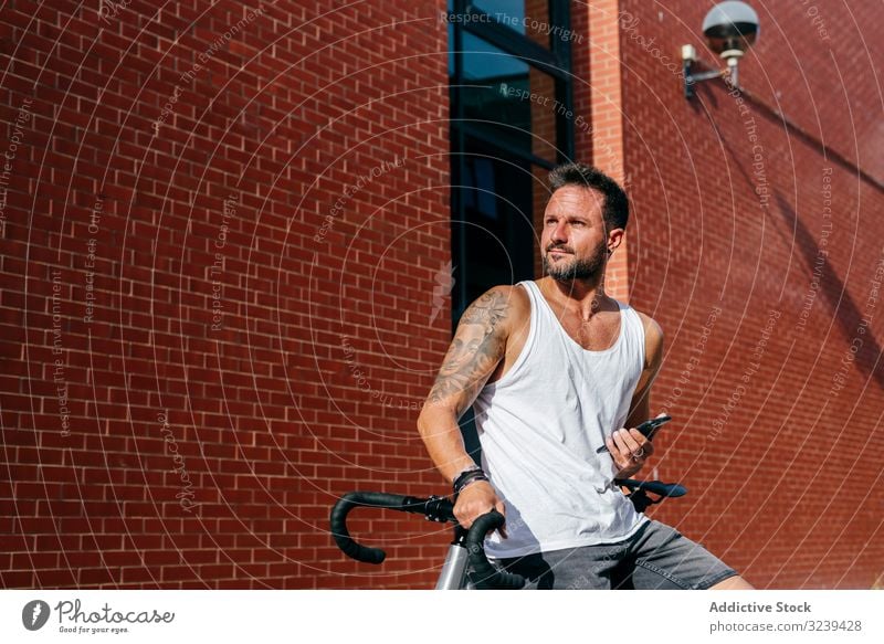 Sportive man with bicycle using phone bike stand mobile phone modern sportive active summer male cyclist smartphone message texting checking reading direction