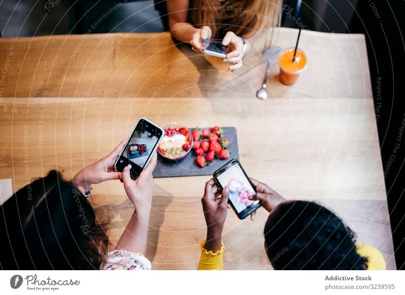 Women taking pictures of healthy food in cafe women taking photo food photography smoothie strawberry smartphone table organic bowl female together mobile