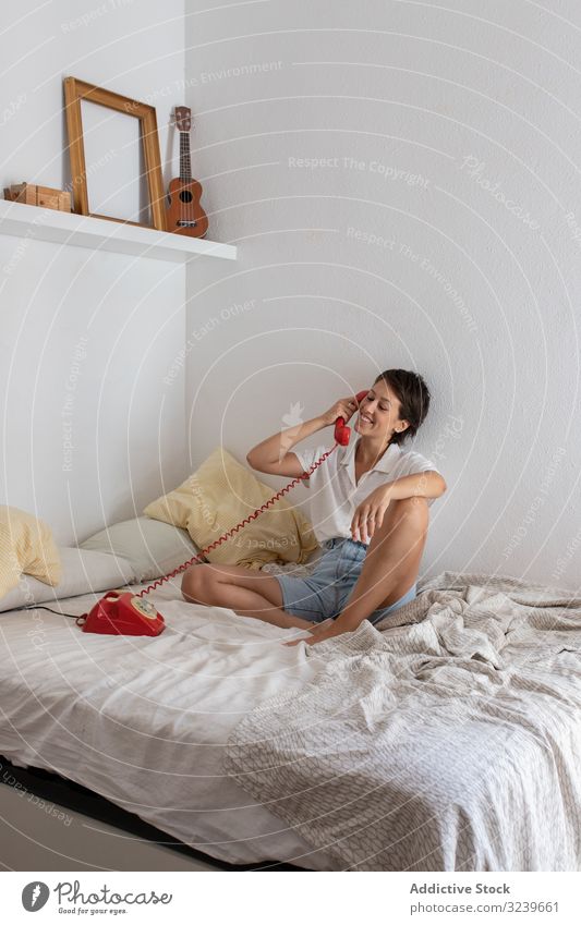Cheerful woman having telephone conversation smile bed listen dialogue call bedroom wall female sit home apartment flat retro vintage communication speak talk