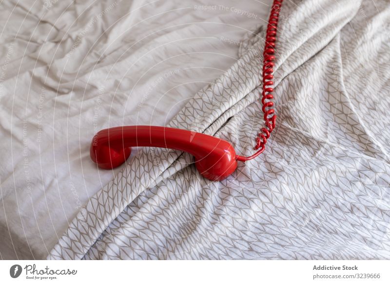 Red telephone handset on bed wire red retro home comfort connection soft vintage call communication duvet sheet apartment flat classic receiver contact dial