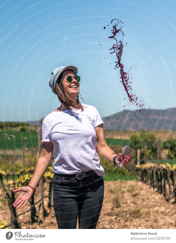 Excited woman spilling red wine from glass in hands tourist excitement drop liquid drink beverage summer fun vacation motion explore tourism freedom dropping