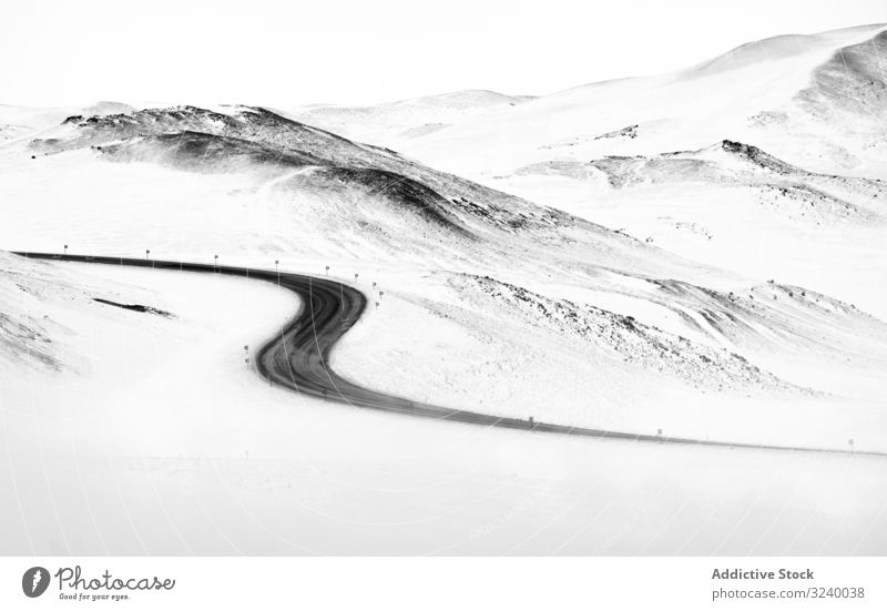 Winding road through snowy hills winter white iceland winding countryside terrain route curvy asphalt path ridge range mountain nature nobody highway frost cold