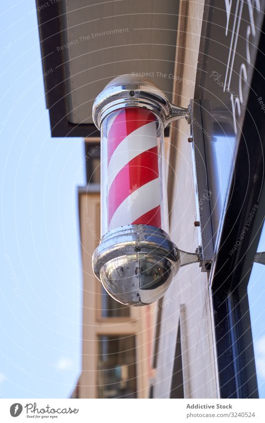 Vertical photo of a rotating post symbolizing the barbershop on the facade signal street red color haircut spiral swirl visual illusion pole trade turning