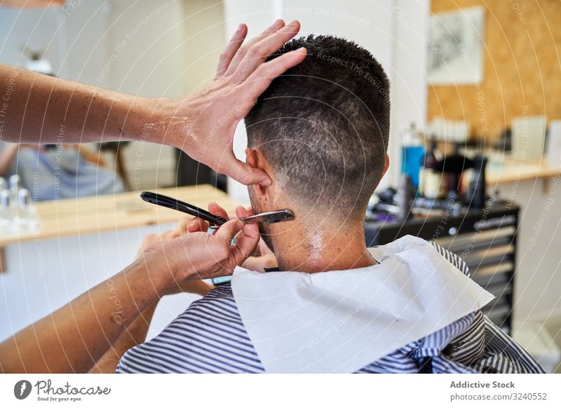 Detail of a barber's hands cutting a client's hair with a razor handmade vintage nape service mirror reflexion shaver barbershop hairstyle furniture work