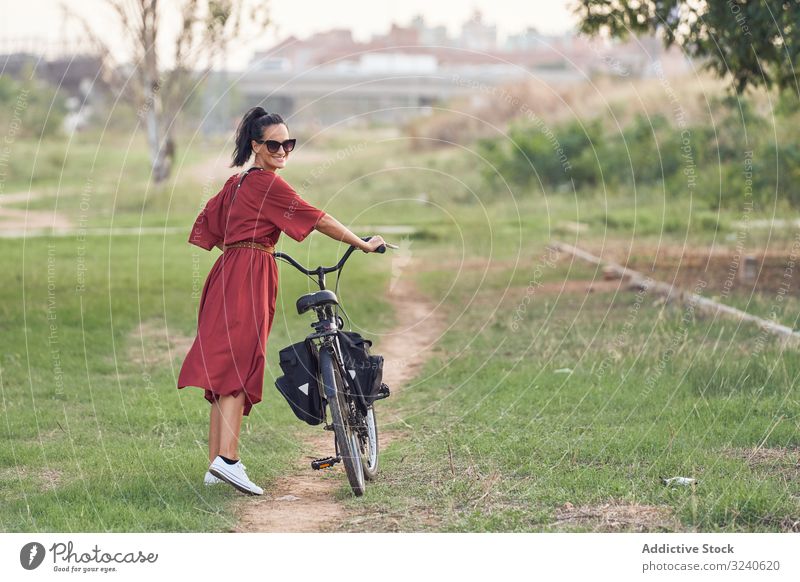 Woman with bicycle walking in park woman path smile casual city summer activity female bike vehicle transport push lifestyle rest relax weekend cheerful lady