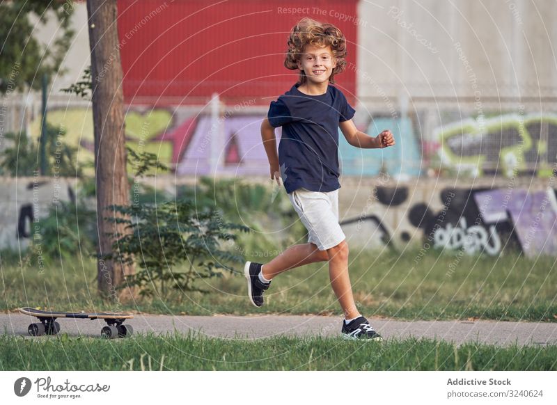 Little skater running in park boy fun skateboard path smile casual city urban lifestyle recreation summer happy joy cheerful kid child way alley childhood