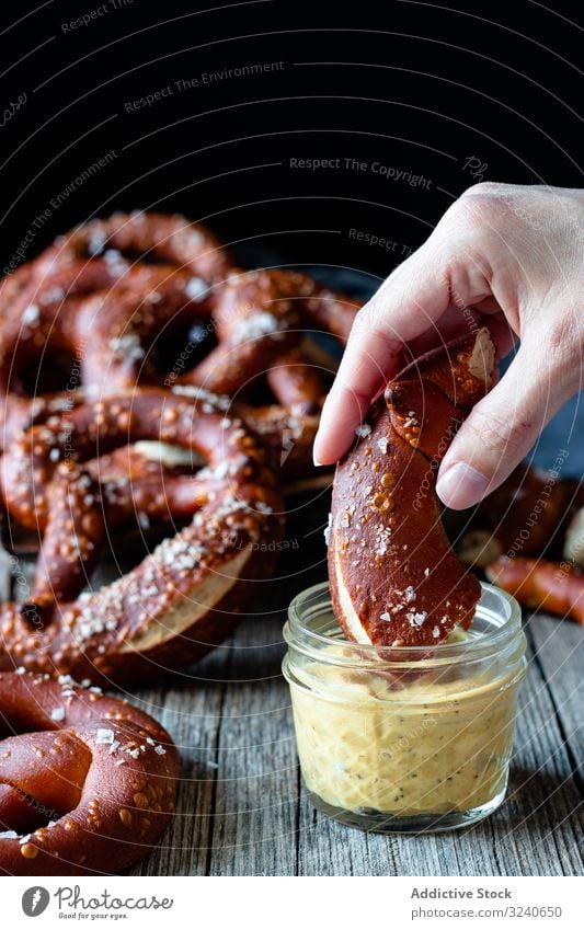 Faceless person eating delicious pretzels dip sauce snack food salted baked cheese fresh tasty german cuisine meal traditional dish jar glass savory gourmet