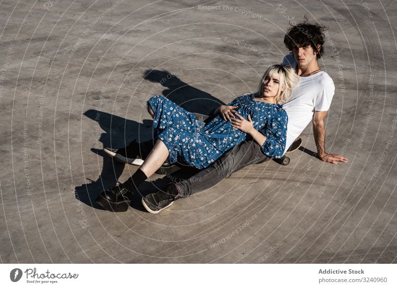 Trendy couple sitting together on skateboard on street dream support love sensual amour soulmate feelings trust calm romance square pleasure boyfriend