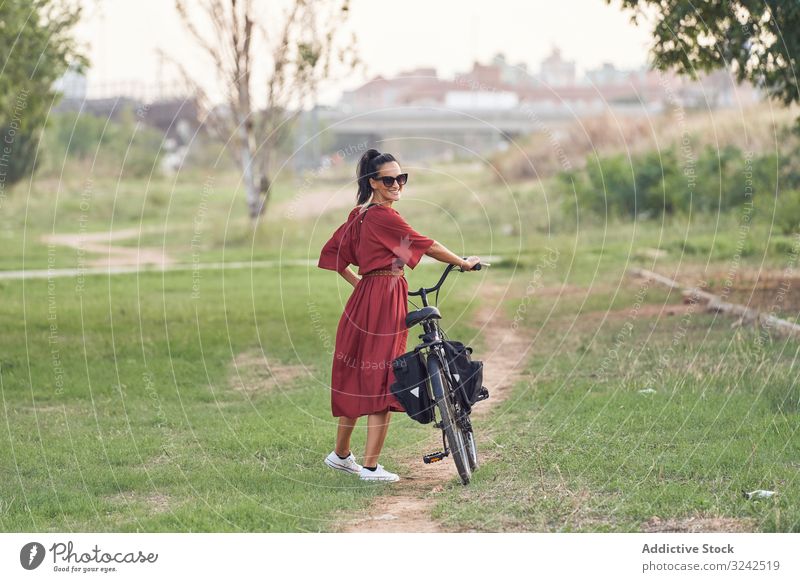 Woman with bicycle walking in park woman path smile casual city summer activity female bike vehicle transport push lifestyle rest relax weekend cheerful lady