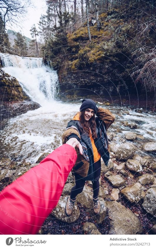 Woman leading by hand person to mountain waterfall woman following walk hold cold forest pond cascade evergreen chill follow me young adult attractive tourist