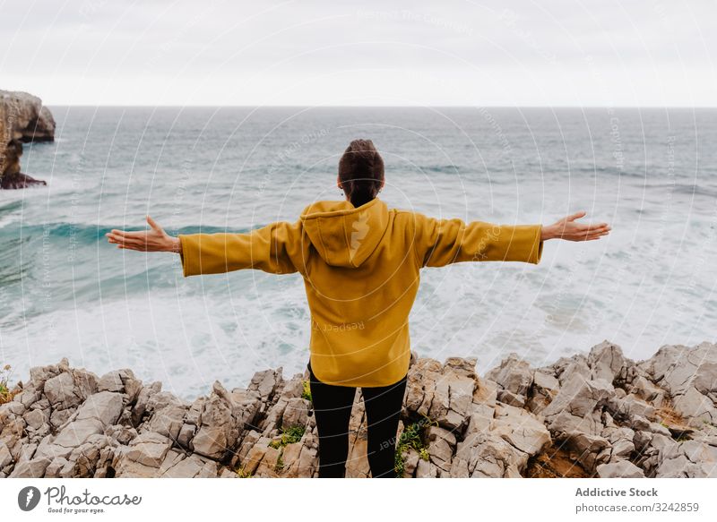 Person in yellow hoodie on stony shore solitude travel wave stone watching dream harmony standing contemplation lonely thoughtful sea ocean horizon freedom