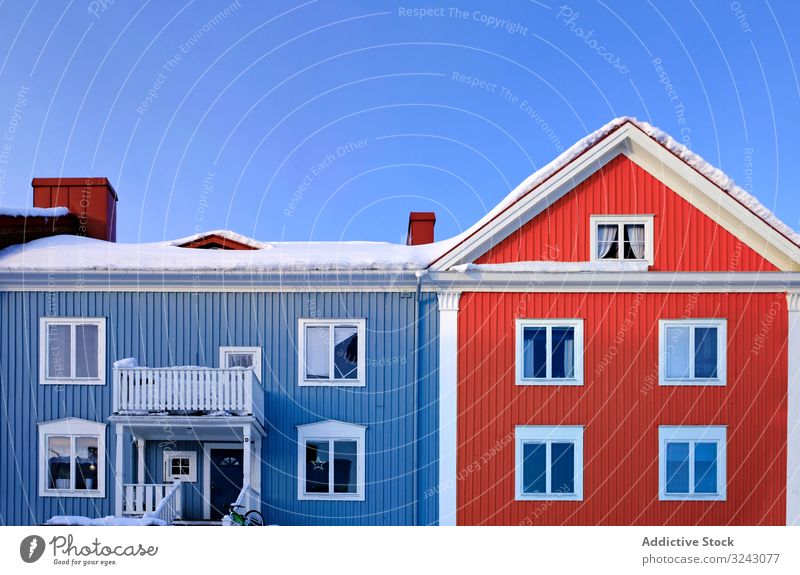 Blue and red cottage in winter countryside village snow house tree leafless sunny daytime sky cloudless calm clean white blue settlement cold cool frost nobody