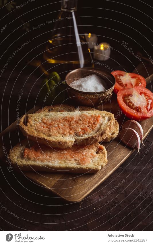 Spices and vegetables near toasts sauce ingredient spice tomato salt garlic basil oil bread cutting board food snack delicious tasty bruschetta yummy delectable