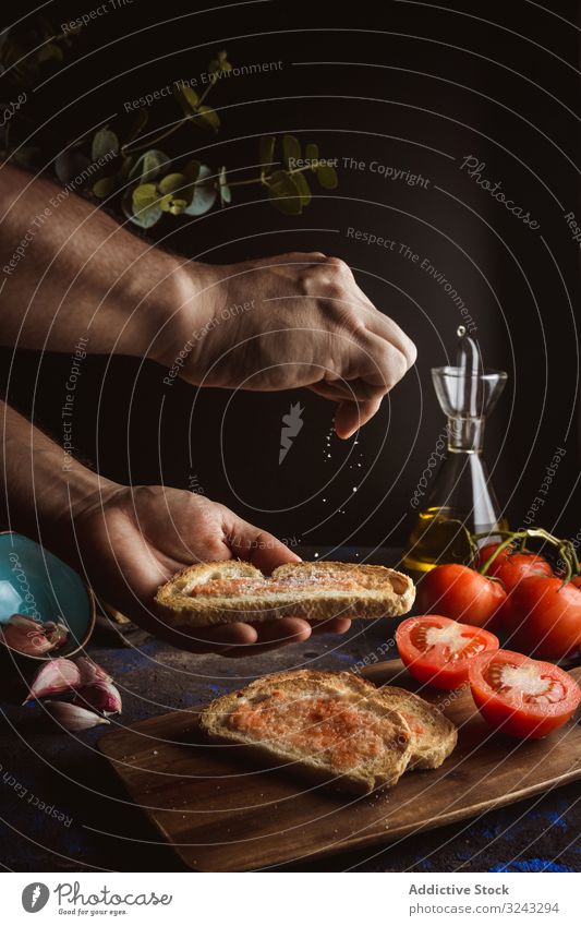 Crop person pouring salt on toasts cook oil bread sauce tomato food dish delicious tasty yummy fresh piece slice dinner meal bruschetta lunch vegetable basil