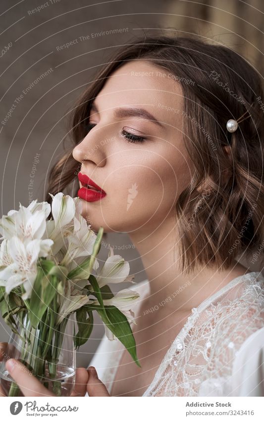 Sensual woman with red lips holding white flowers and dreaming white dress wedding dress sensual gentle makeup charm bride tender beauty calm pensive serenity