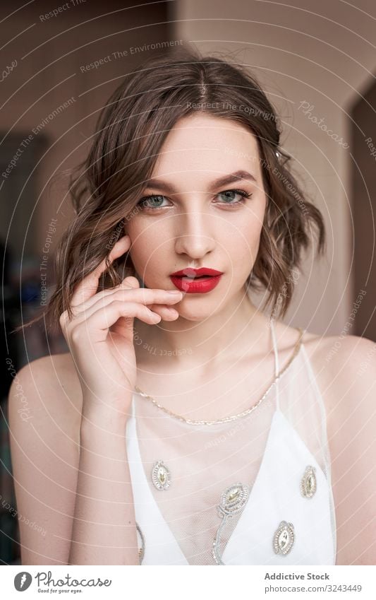Gorgeous young confident woman with red lips looking at camera white dress trendy sensual calm makeup pensive charm cunning plan beauty think gaze female