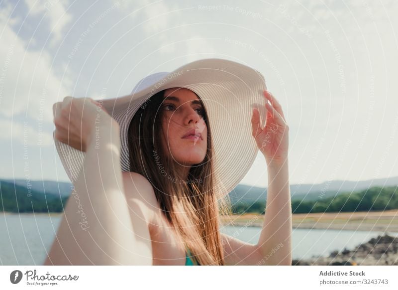 Young woman in hat resting on beach lake summer young dreamy cloudy sky female water vacation weekend lifestyle nature countryside headgear weather lady calm