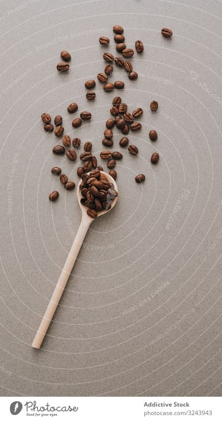 Coffee beans in spoon on gray surface coffee roasted dark scatter flavor scoop gourmet table grain aroma coffee beans brown simple natural food ingredient fresh