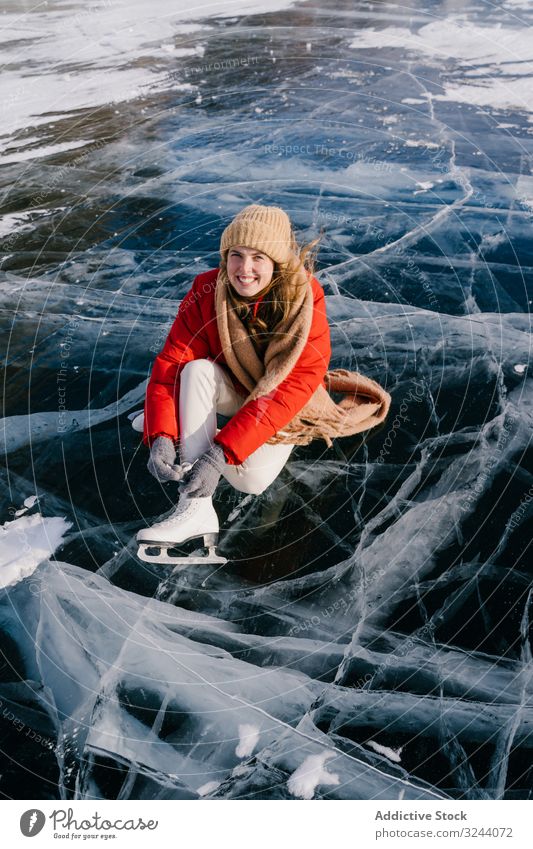 Woman sitting on frozen river and tying the shoelaces woman snow boots skates putting on winter change siberia cold sportswear russia female white adventure