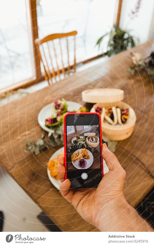 Photographer taking picture of food with smartphone photo taking photo food photography hand mobile cellphone table meal photographer plate dish wooden